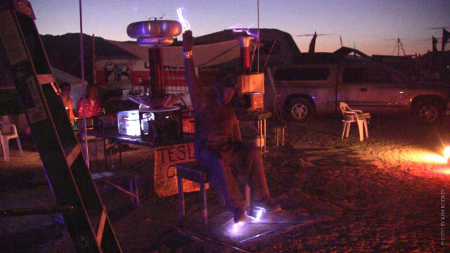 Kilovolt's feet spark from Tesla Coil to ground at Burning Man.